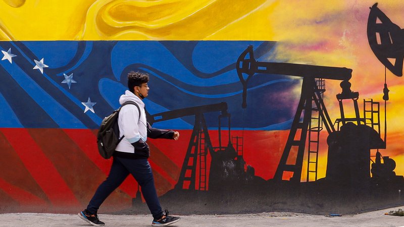 Ein Passant geht ein einem Wandgemälde vorbei, die Tiefpumpen zur Ölförderung über einer Flagge von Venezuela darstellt | Bild: picture alliance/dpa | Jesus Vargas Ein Passant geht ein einem Wandgemälde vorbei, die Tiefpumpen zur Ölförderung über einer Flagge von Venezuela darstellt