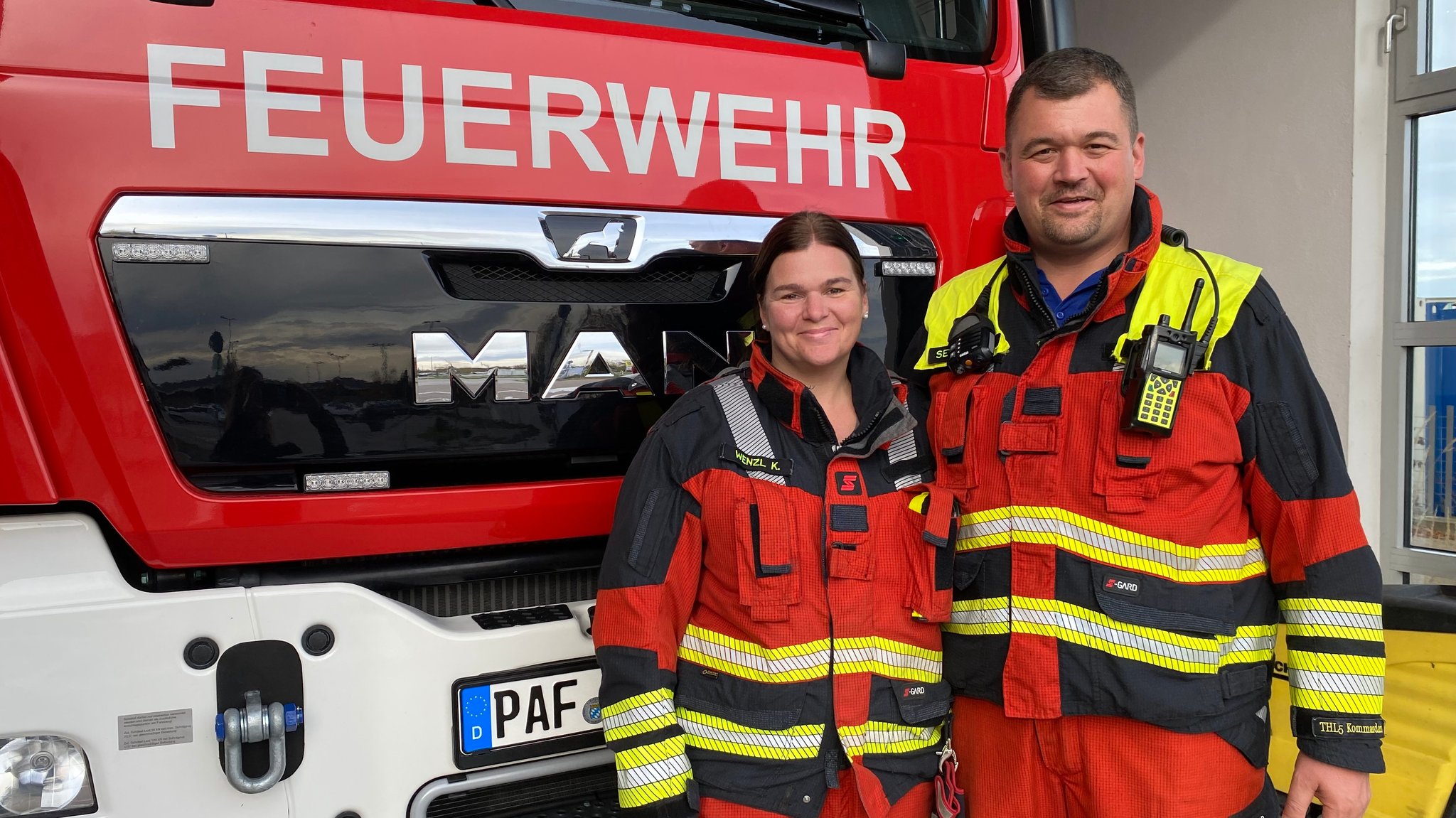 Feuerwehrleute vor Feuerwehrauto. 