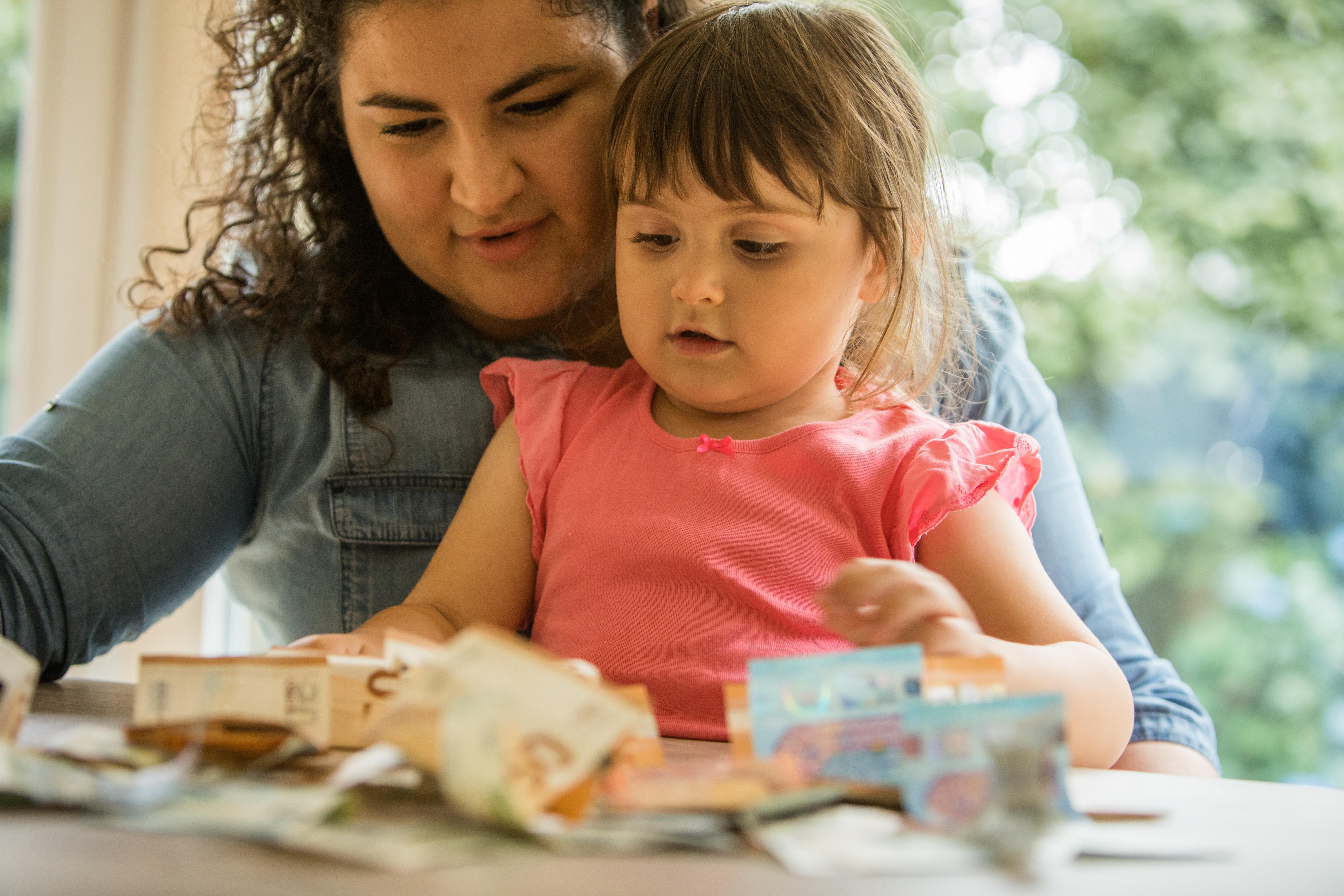Ein kleines Mädchen und seine Mutter sitzen vor Geldscheinen