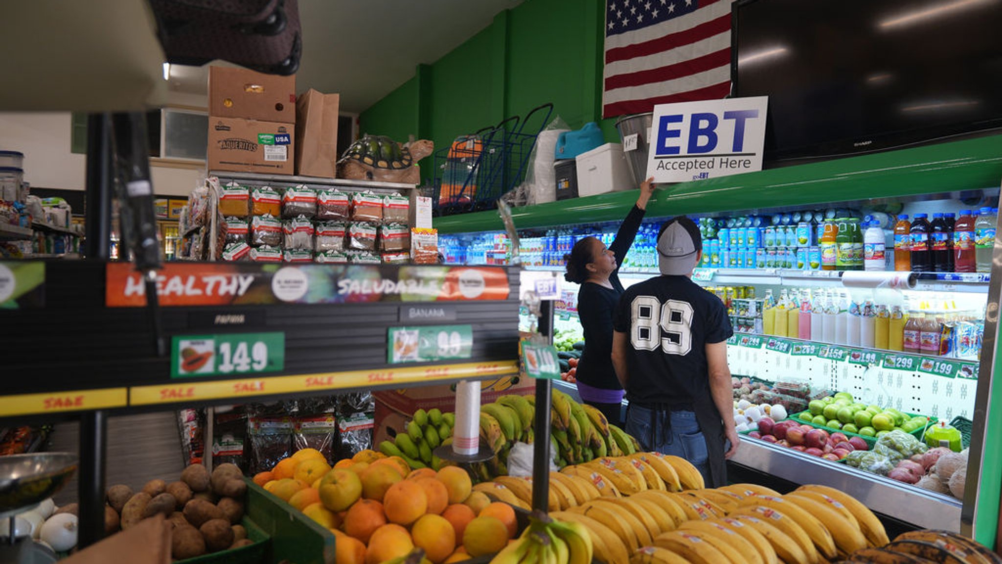 31.10.2025, USA, Los Angeles: Die Managerin des El Recuerdo Market, Cecilia Benitez, stellt in Los Angeles ein Banner mit der Aufschrift "EBT (Electronic Benefit Transfer) Accepted Here" auf, nachdem zwei Bundesrichter die Regierung von Präsident Donald Trump angewiesen hatten, SNAP während des Stillstands der Regierung weiter zu finanzieren. Foto: Damian Dovarganes/AP/dpa +++ dpa-Bildfunk +++