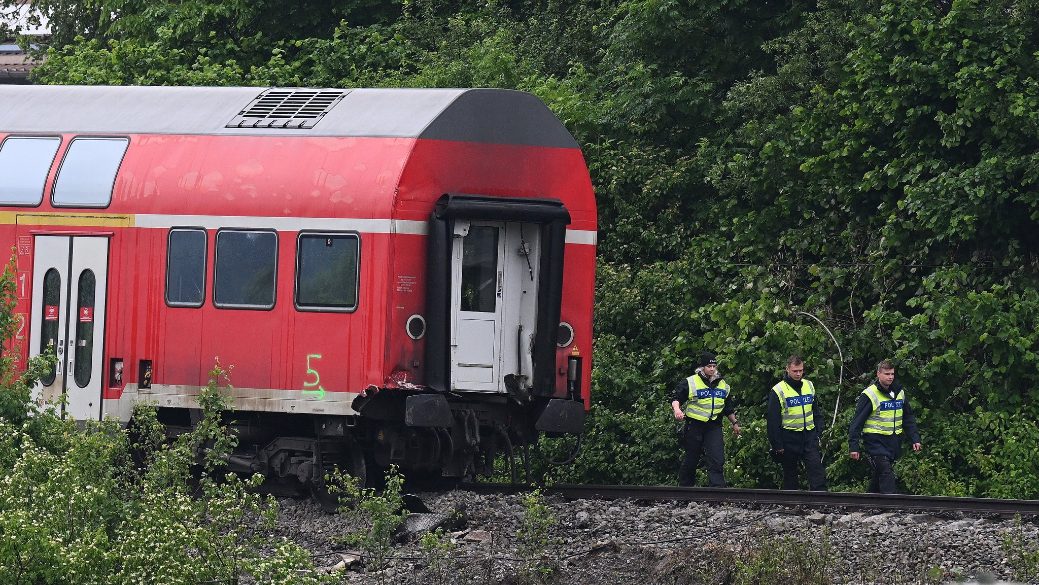 Polizisten stehen neben einem der beschädigten Waggons nach dem Zugunglück von Burgrain auf dem Gleis. 