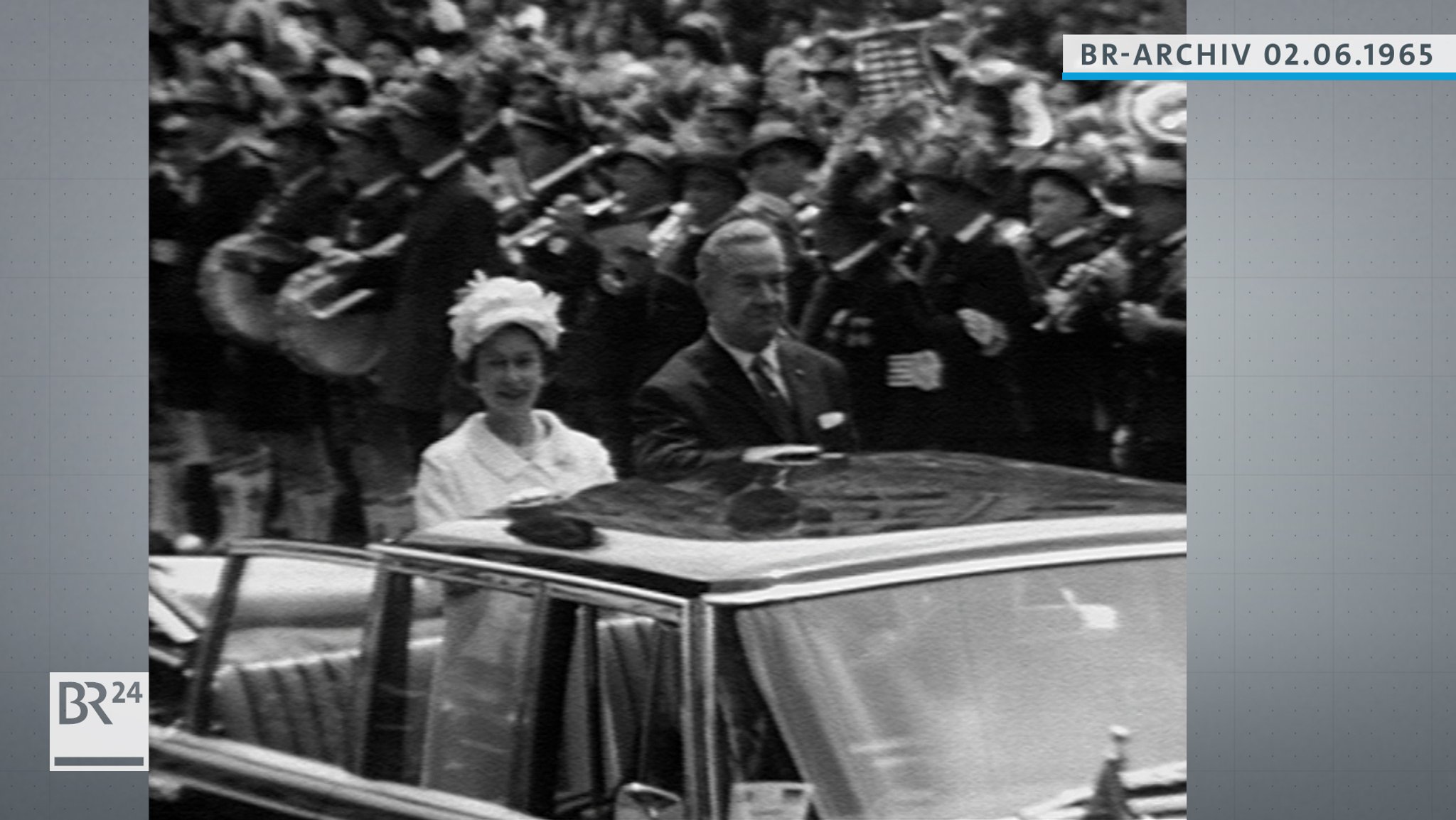 Königin Elisabeth II. im offenen Wagen stehend