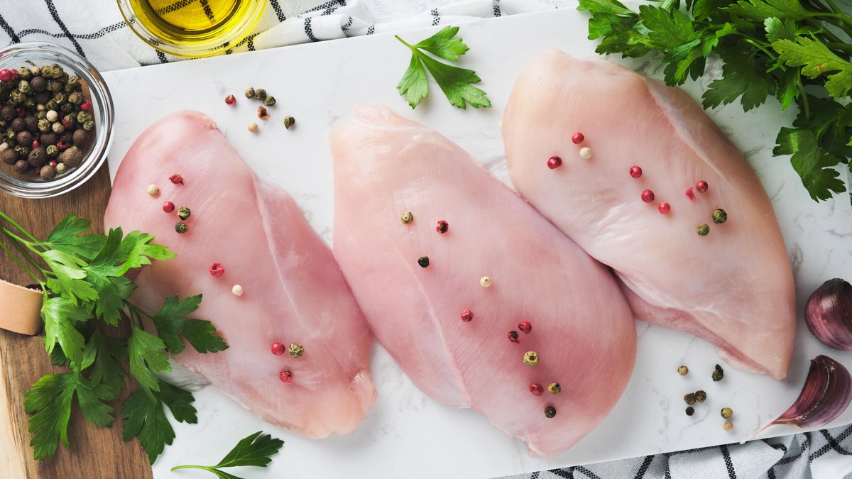Drei rohe Hähnchenfilets auf einer Arbeitsplatte mit Gewürzen