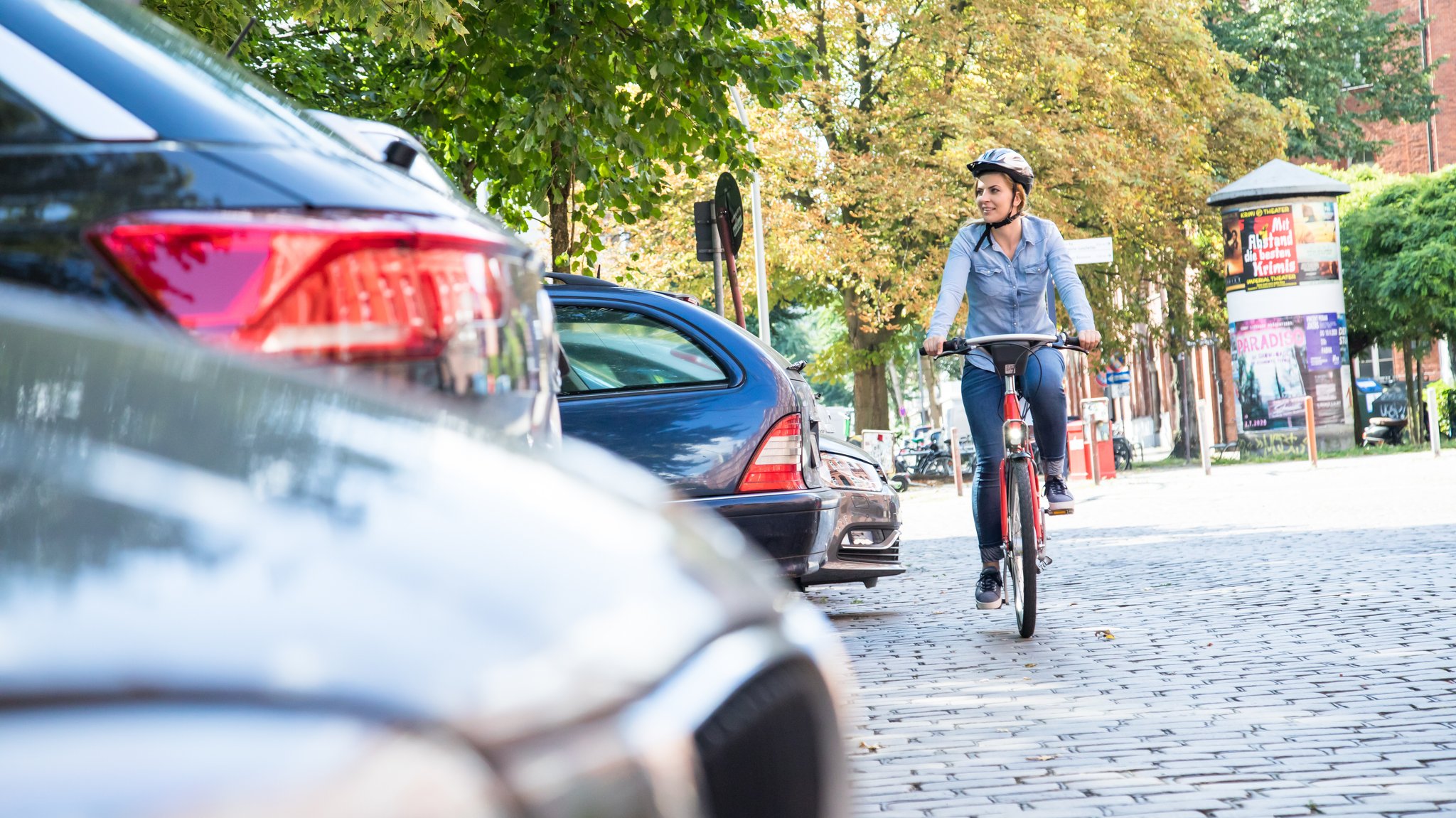 Symbolbild: Fahrradfahrerin und Autos in der Stadt