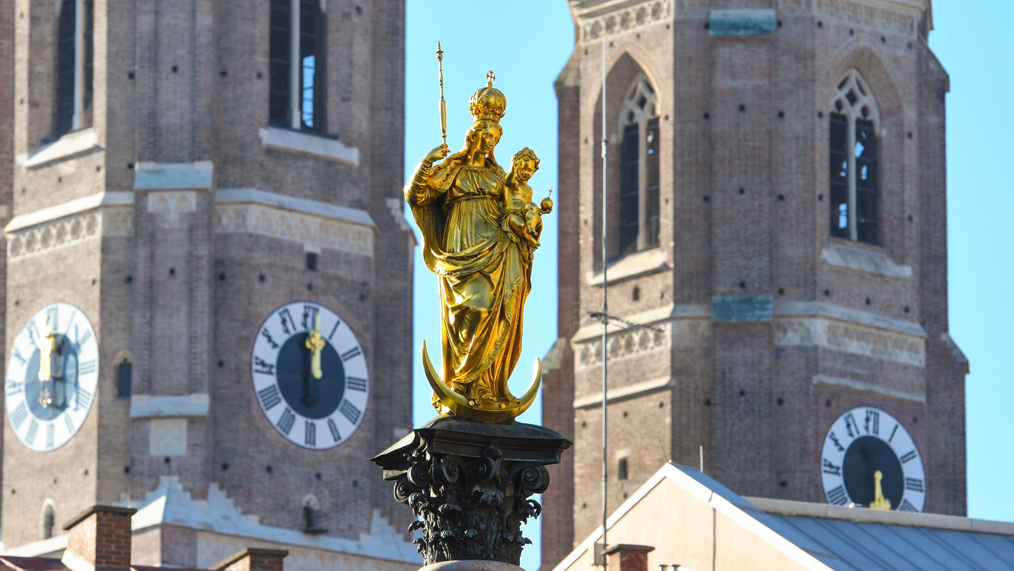 Die Türme der Frauenkirche in München mit der Marienstatue im Vordergrund.