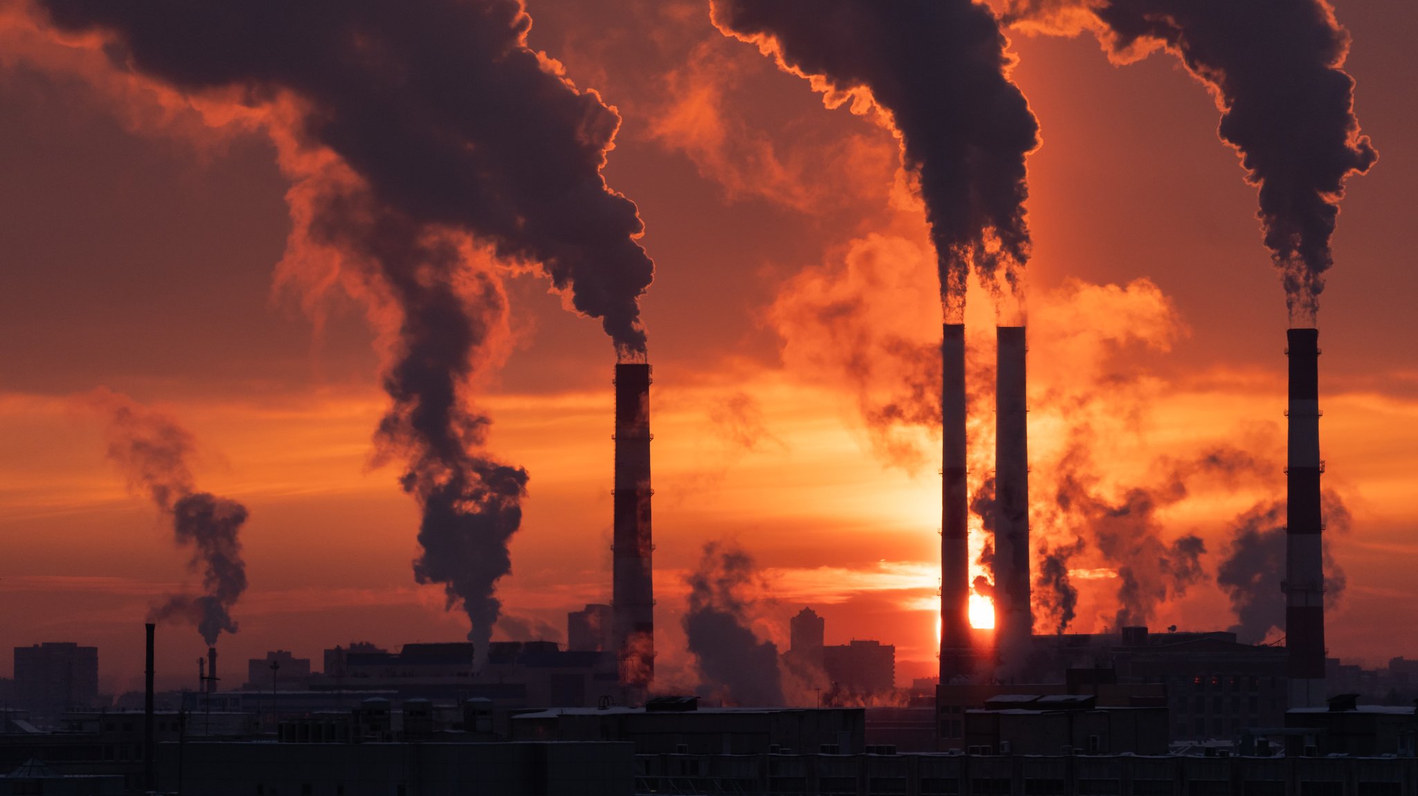 Dichte Rauchschwaden steigen aus den Schornsteinen eines Industriegebiets vor einem dramatischen Sonnenuntergang auf. | Bild: stock.adobe.com/DimaBerlin Dichte Rauchschwaden steigen aus den Schornsteinen eines Industriegebiets vor einem dramatischen Sonnenuntergang auf.