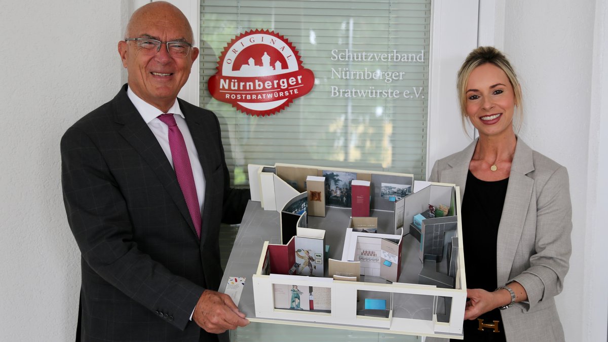 Dr. Rainer Heimler und Nina Weiß vom Schutzverband Nürnberger Bratwürste halten ein Modell des geplanten Bratwurstmuseums in den Händen.