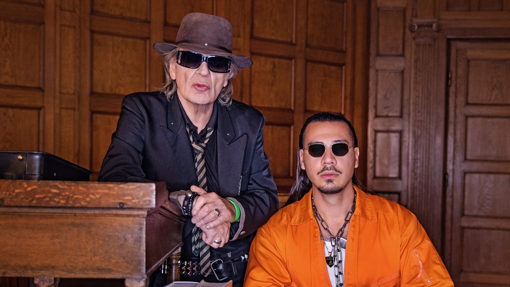 Udo Lindenberg mit Hut und Sonnenbrille neben Aapche 207, in oranger Jacke und ebenfalls mit Sonnenbrille