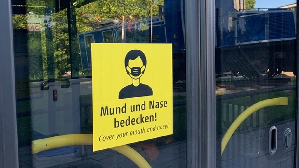 Ein Schild weist an einer Bustür auf einen Mund-Nasen-Schutz hin.