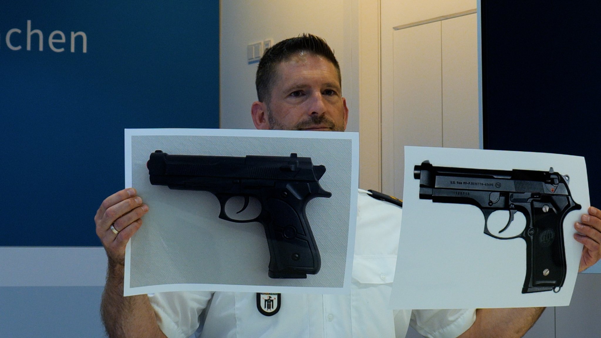 Ein Polizeisprecher zeigt das Bild einer Softair-Waffe (links im Bild) und rechts im Bild eine echte Beretta-Pistole | Bild: BR Ein Polizeisprecher zeigt das Bild einer Softair-Waffe (links im Bild) und rechts im Bild eine echte Beretta-Pistole
