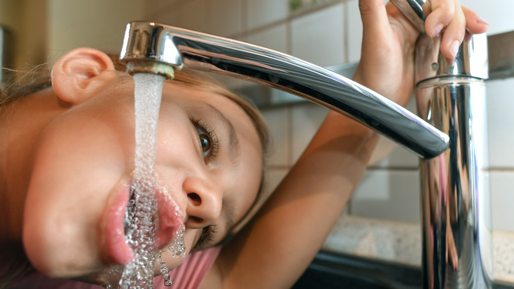 Kein Grund zur Sorge: Das Trinken von Leitungswasser ist ungefährlich, sagen Experten. Trinkwasser ist eines der am besten überwachten Lebensmittel. Im Bild: Ein Mädchen trinkt Leitungswasser aus einem Wasserhahn in der heimischen Küche.