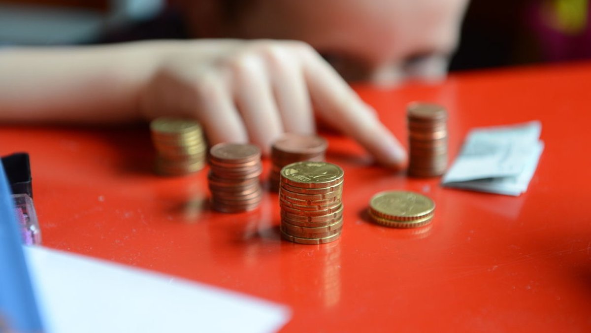 Ein fünfjähriger Junge sitzt an einem roten Tisch und zählt sein gespartes Taschengeld. (Symbolbild)