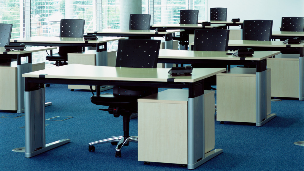 Ein menschenleeres Großraumbüro voller leerer Schreibtische und Stühle. 