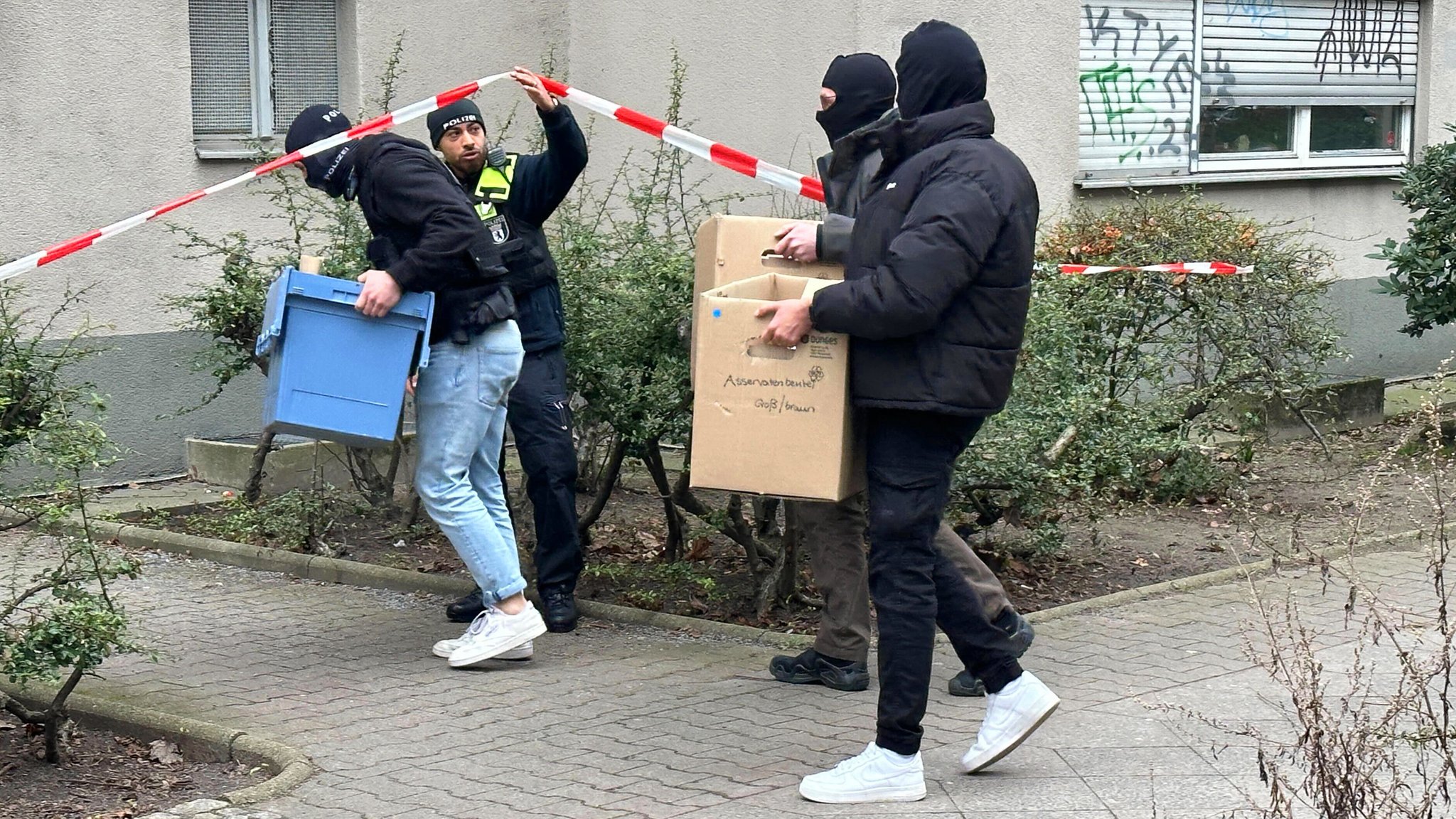 Ermittler gehen mit Kisten und Kartons in das Wohnhaus der früheren RAF-Terroristin Daniela Klette in Berlin.