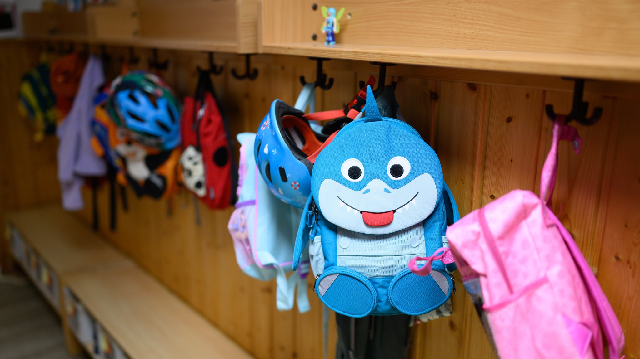 Kinderrucksäcke hängen in der Garderobe einer Kita.