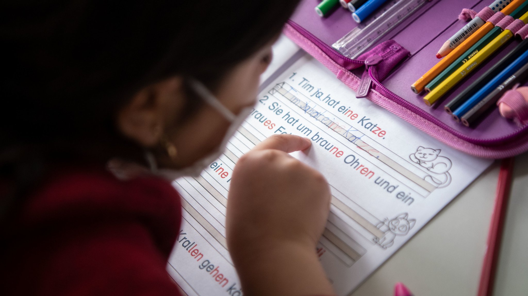 Ein Kind liest in einem Übungsheft für Grundschüler