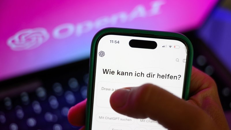 Ein Smartphone mit dem KI-Chatbot ChatGPT ist vor dem Logo des US-Softwareunternehmens OpenAI zu sehen. | Bild: dpa-Bildfunk/Hendrik Schmidt Ein Smartphone mit dem KI-Chatbot ChatGPT ist vor dem Logo des US-Softwareunternehmens OpenAI zu sehen.