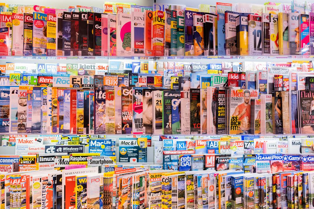 Zeitschriften liegen in Regalen in einem Kiosk.