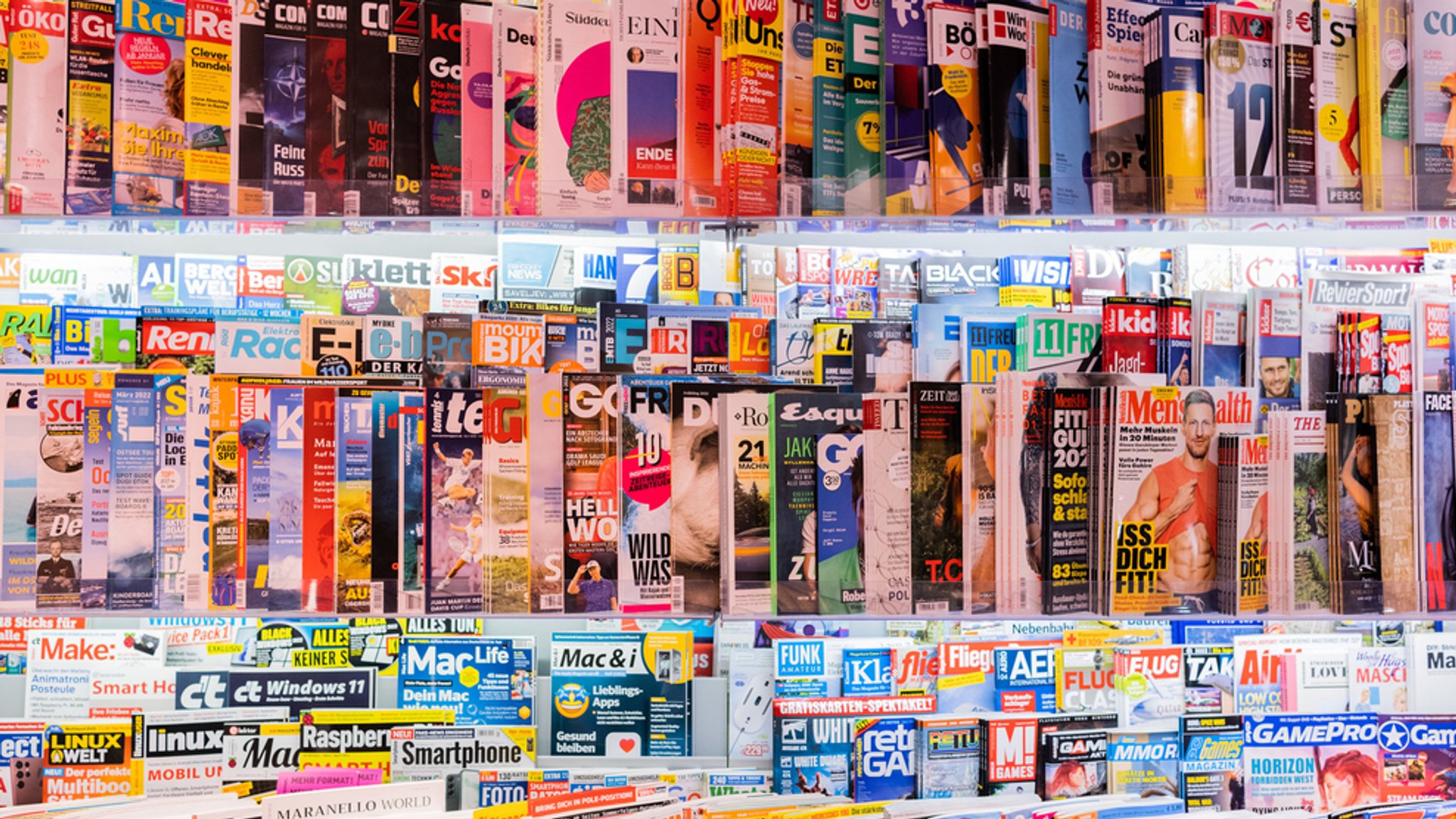 Zeitschriften liegen in Regalen in einem Kiosk.