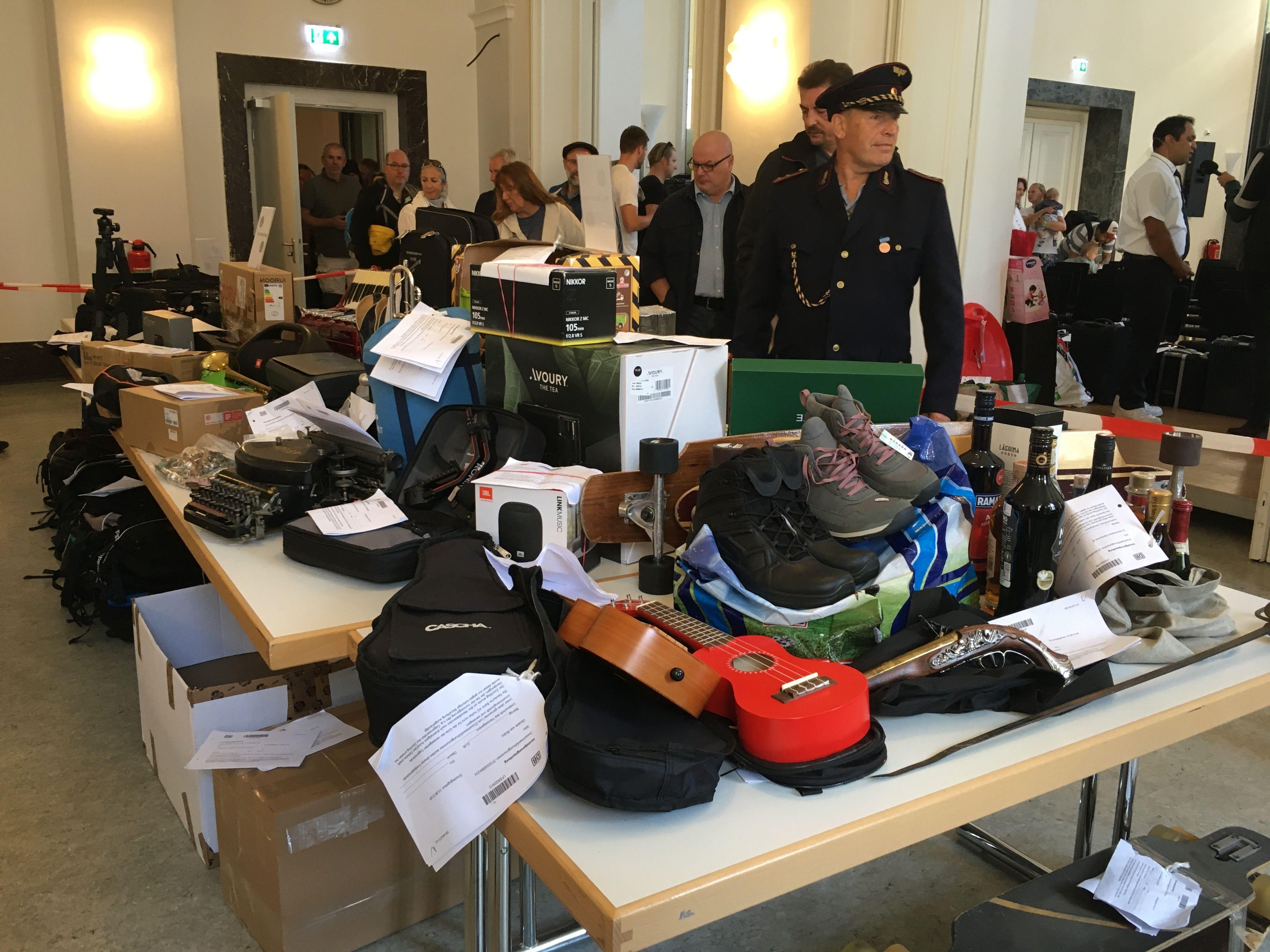 Menschen besichtigen kurz vor einer Versteigerung verschiedene Gegenstände auf Tischen.