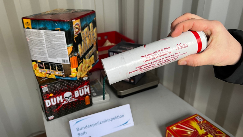 Feuerwerkskörper liegen auf einem Tisch der Bundespolizeiinspektion Selb, einen Böller hält eine Hand so, dass die (unechten) Prüfzeichen sichtbar sind. | Bild: BR/Sandra Jozipovic Feuerwerkskörper liegen auf einem Tisch der Bundespolizeiinspektion Selb, einen Böller hält eine Hand so, dass die (unechten) Prüfzeichen sichtbar sind.