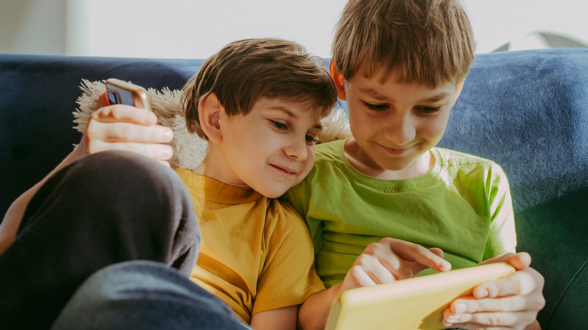 Zwei Jungen schauen in ein Handy. Kinder nutzen Social Media zu oft und zu lange, das fand eine Studie heraus.