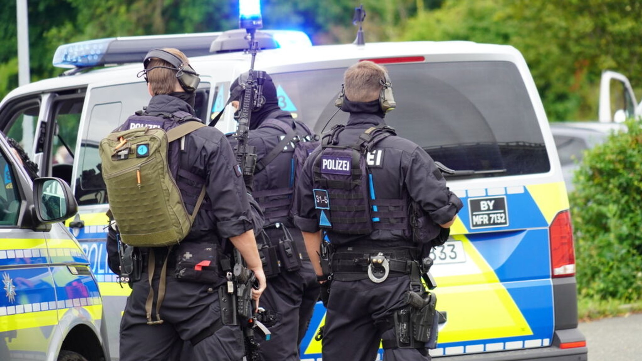 07.07.2024, Bayern, Altdorf: Einsatzkräfte der Polizei bereiten sich neben ihren Fahrzeugen auf den Einsatz vor. In Altdorf bei Nürnberg ist die Polizei wegen Bränden und einer "Bedrohungslage" zu einem größeren Einsatz ausgerückt.