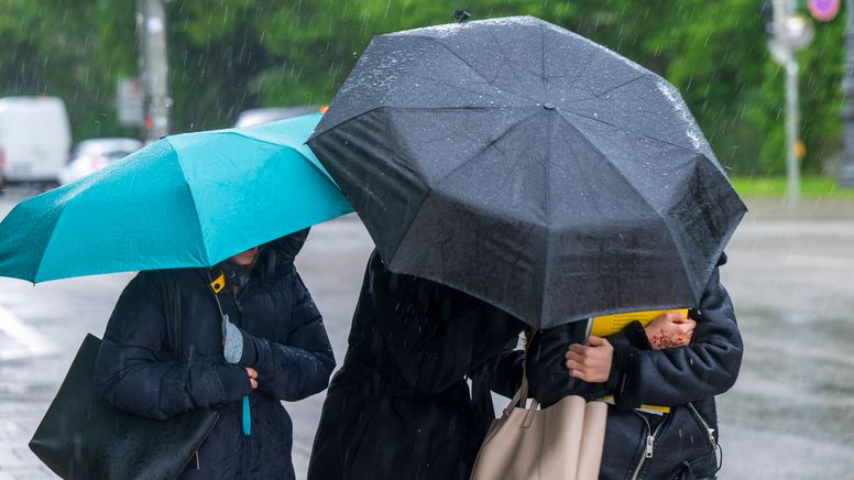 München: Drei Frauen laufen bei einsetzendem Regen mit Schirmen über den Königsplatz.  | Bild:dpa-Bildfunk/Peter Kneffel