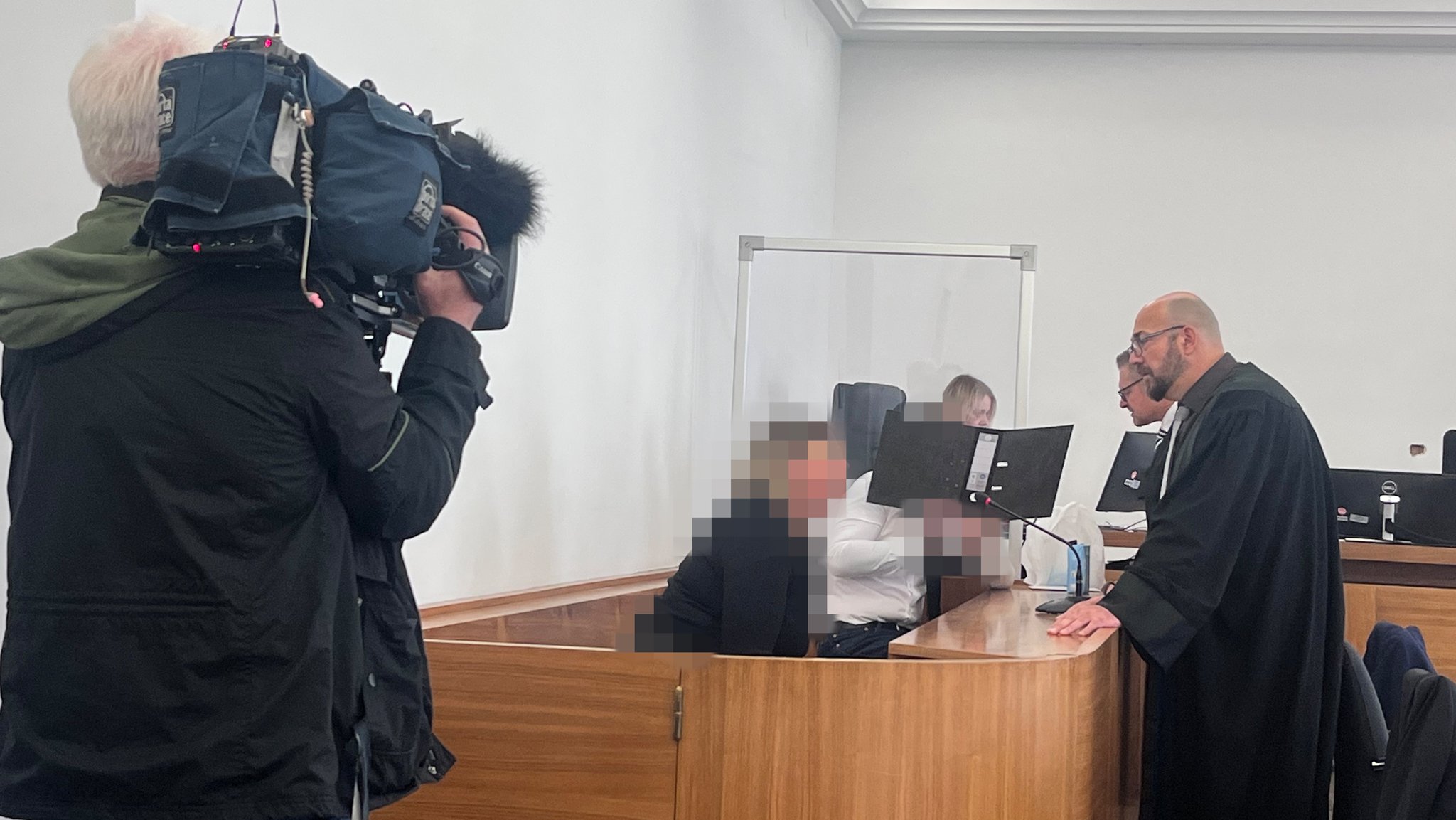 Die beiden Angeklagten auf der Anklagebank, der 40-Jährige verbirgt sein Gesicht hinter einem Aktenordner.