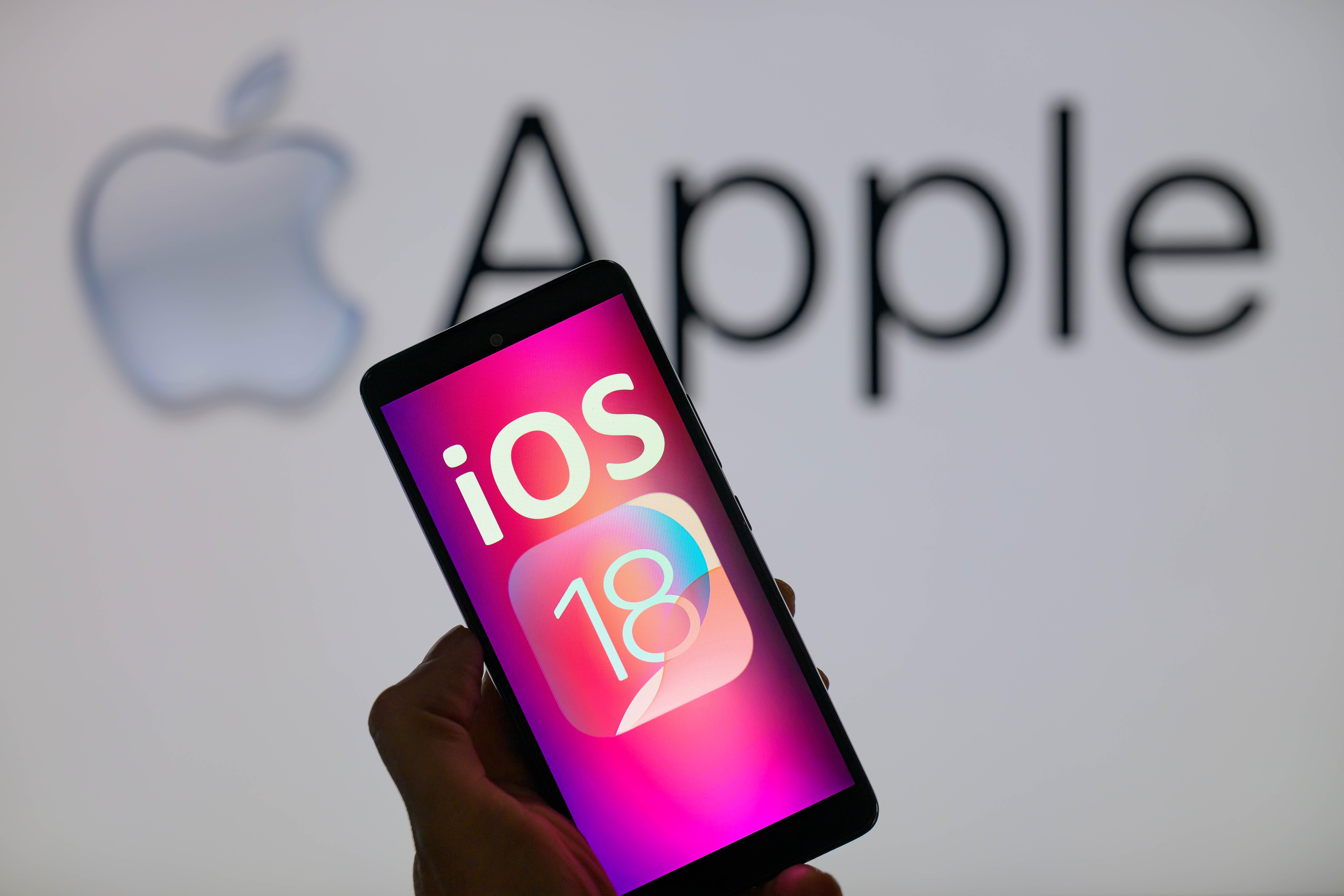 Smartphone mit iOS 18 Schrift vor Apple-Hintergrund