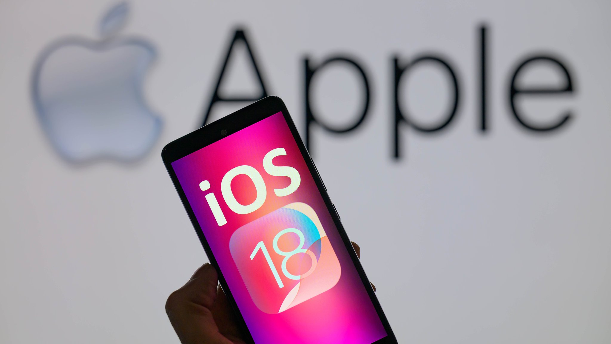 Smartphone mit iOS 18 Schrift vor Apple-Hintergrund