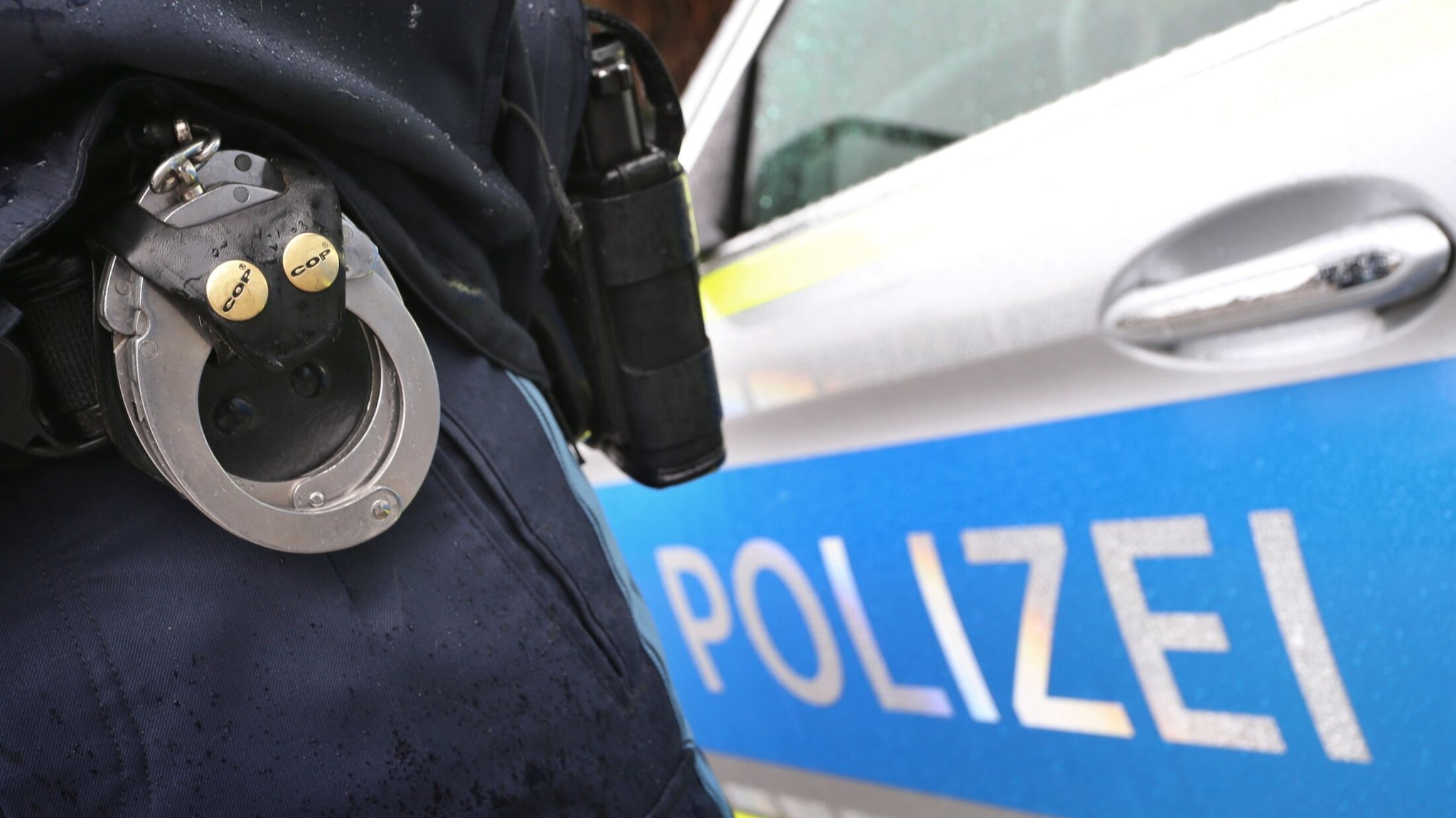 Ein Polizist mit Handschellen und einer Pistole am Gürtel steht vor einem Streifenwagen. | Bild: dpa-Bildfunk/Karl-Josef Hildenbrand Ein Polizist mit Handschellen und einer Pistole am Gürtel steht vor einem Streifenwagen.
