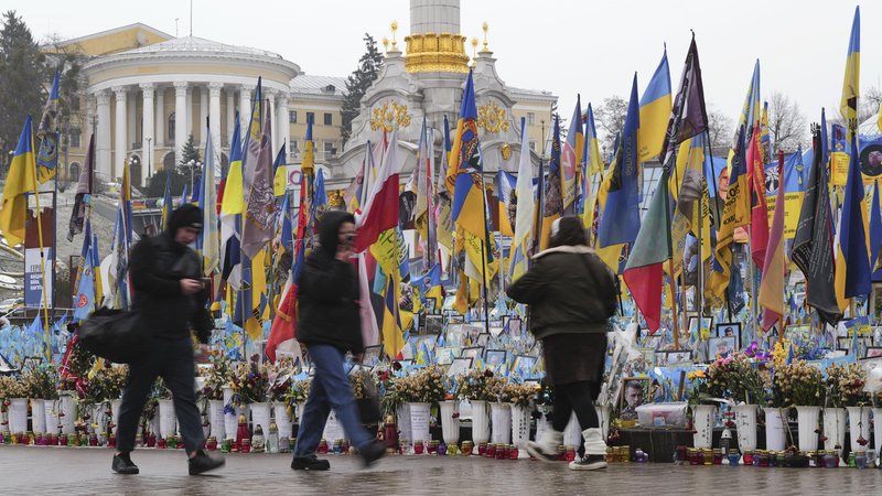 Passanten vor Blumenvasen und ukrainischen Flaggen | Bild: Kyodo/Picture Alliance Passanten vor Blumenvasen und ukrainischen Flaggen