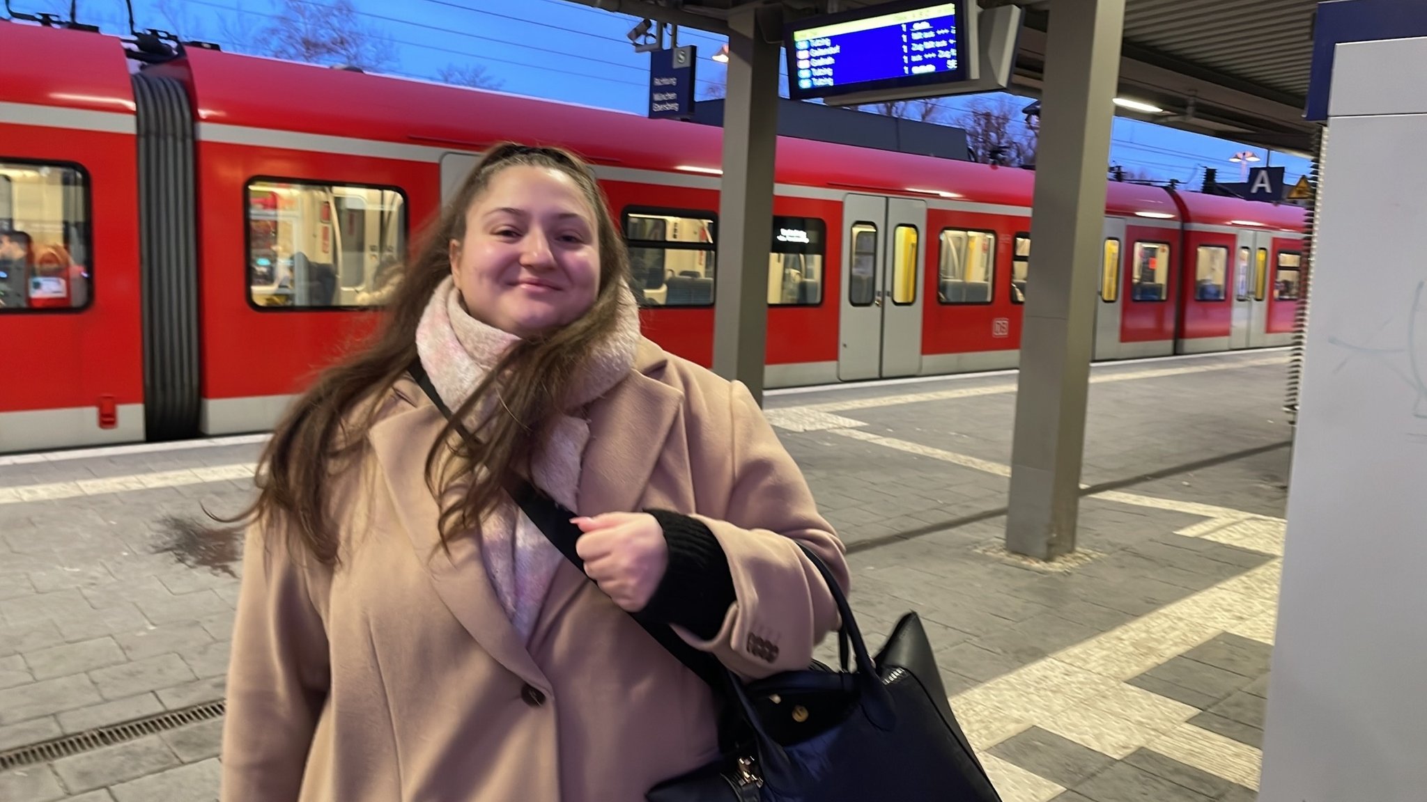 Helena wartet am Bahnsteig in Grafing, im Hintergrund ist eine S-Bahn