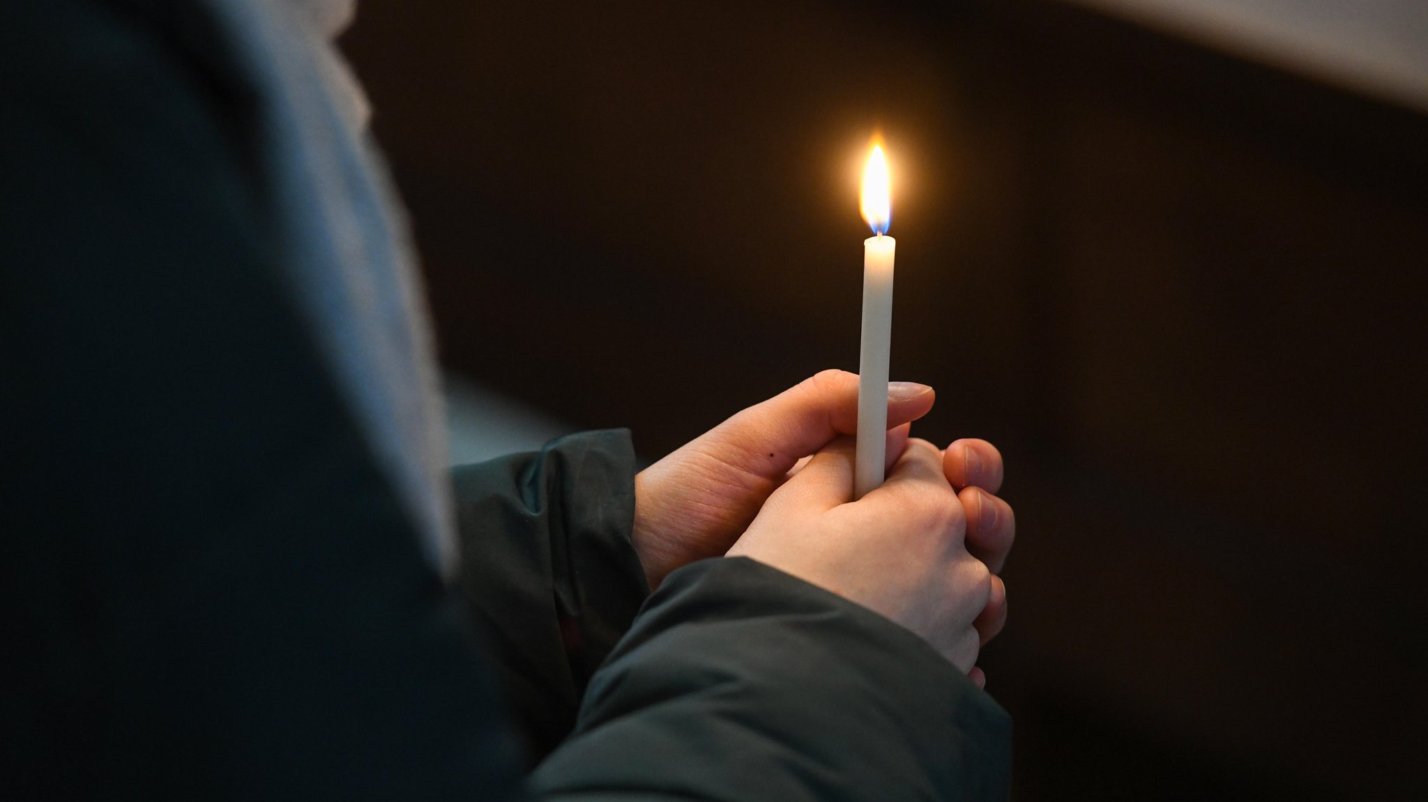 Ein Gottesdienstbesucher an Lichtmess hält eine Kerze in der Hand. 