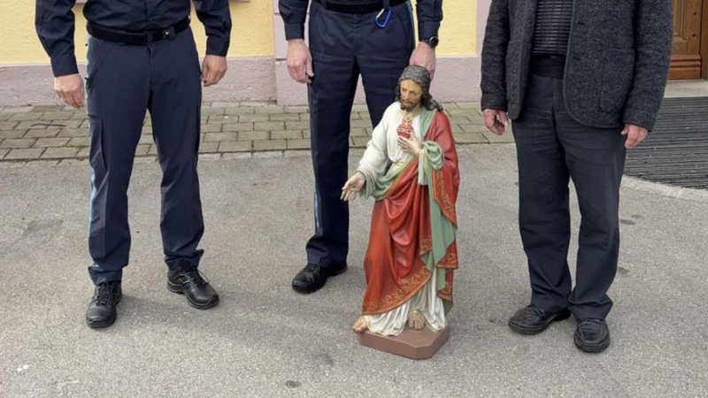 Polizeihauptkommissare Michael Laugwitz und Markus Dösinger stehen zusammen mit Pfarrer Bernhard Endres hinter der gefundenen Jesusfigur, alle drei lächeln. | Bild: PP SWS Polizeihauptkommissare Michael Laugwitz und Markus Dösinger stehen zusammen mit Pfarrer Bernhard Endres hinter der gefundenen Jesusfigur, alle drei lächeln.