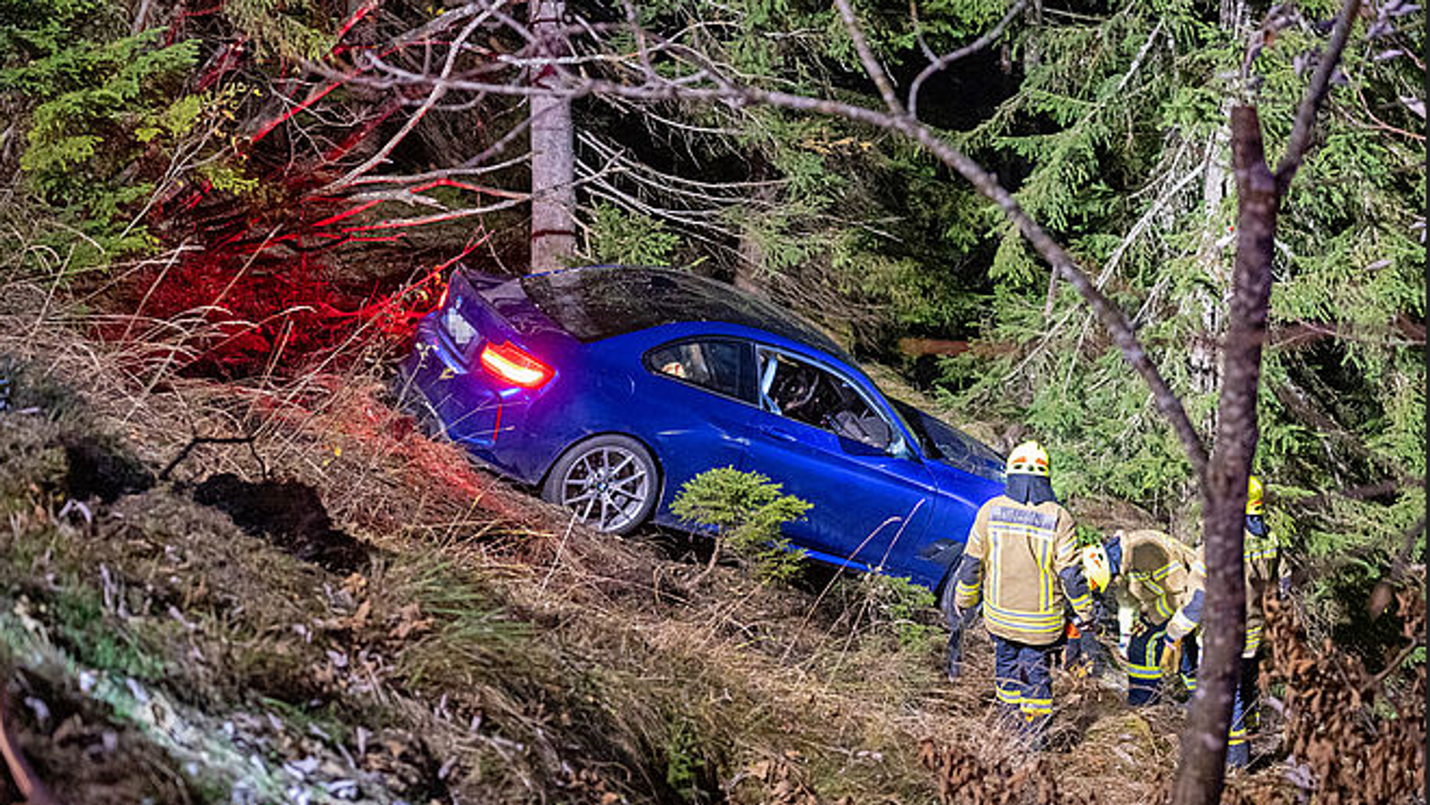 Der PS-starke BMW im Wald an der Böschung und Rettungskräfte