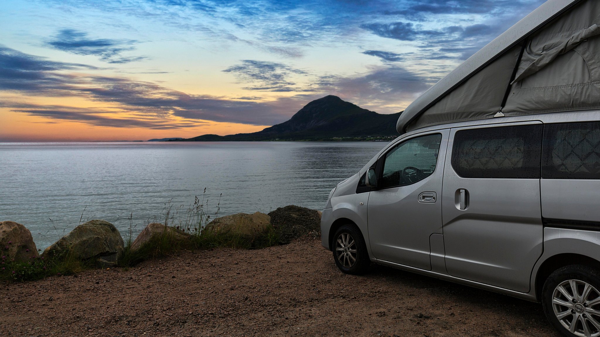 Camper steht auf einem Parkplatz am Meer.