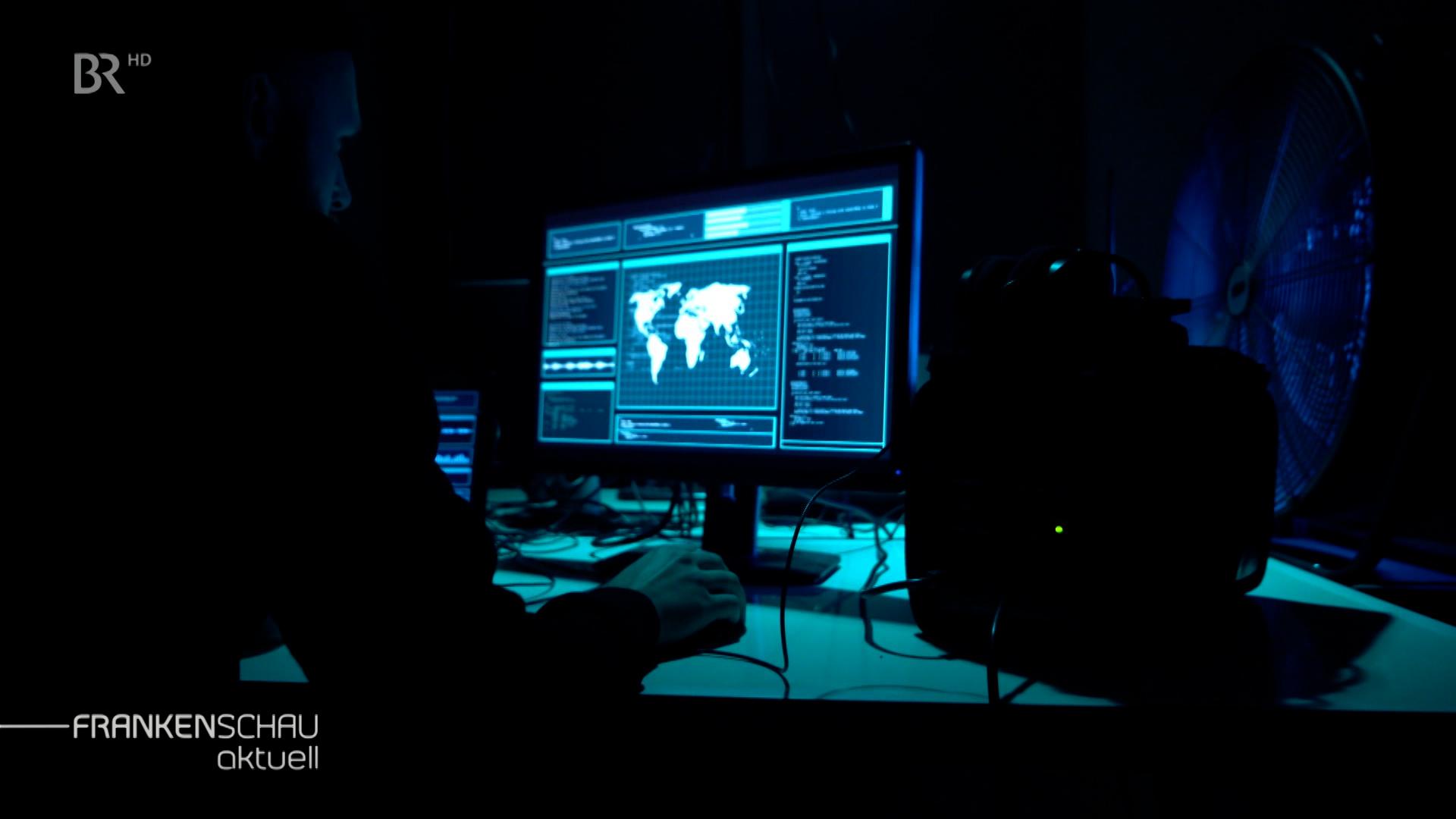 Eine Person sitzt in einem dunklen Raum an einem Computer.