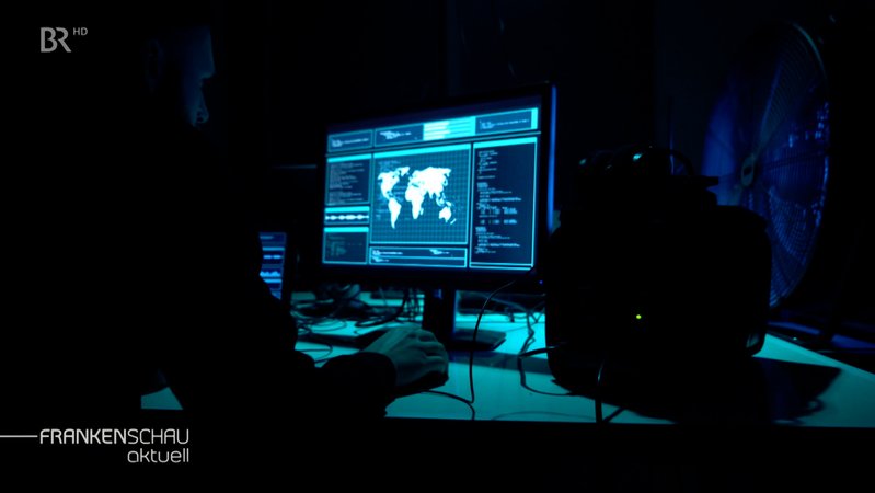 Eine Person sitzt in einem dunklen Raum an einem Computer. | Bild: BR Eine Person sitzt in einem dunklen Raum an einem Computer.