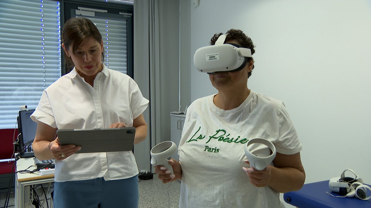 Eine Patientin mit einer VR-Brille (rechts) steht neben einer Frau im Uniklinikum Erlangen