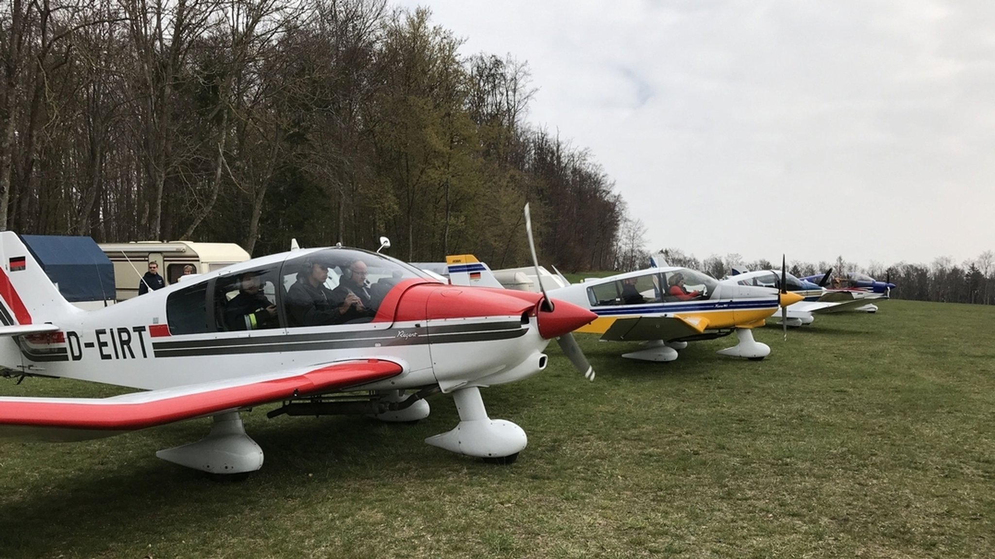 Ehrenamtliche Piloten der Luftrettungsstaffel sitzen in ihren Flugzeugen, im Hintergrund sind Bäume zu sehen