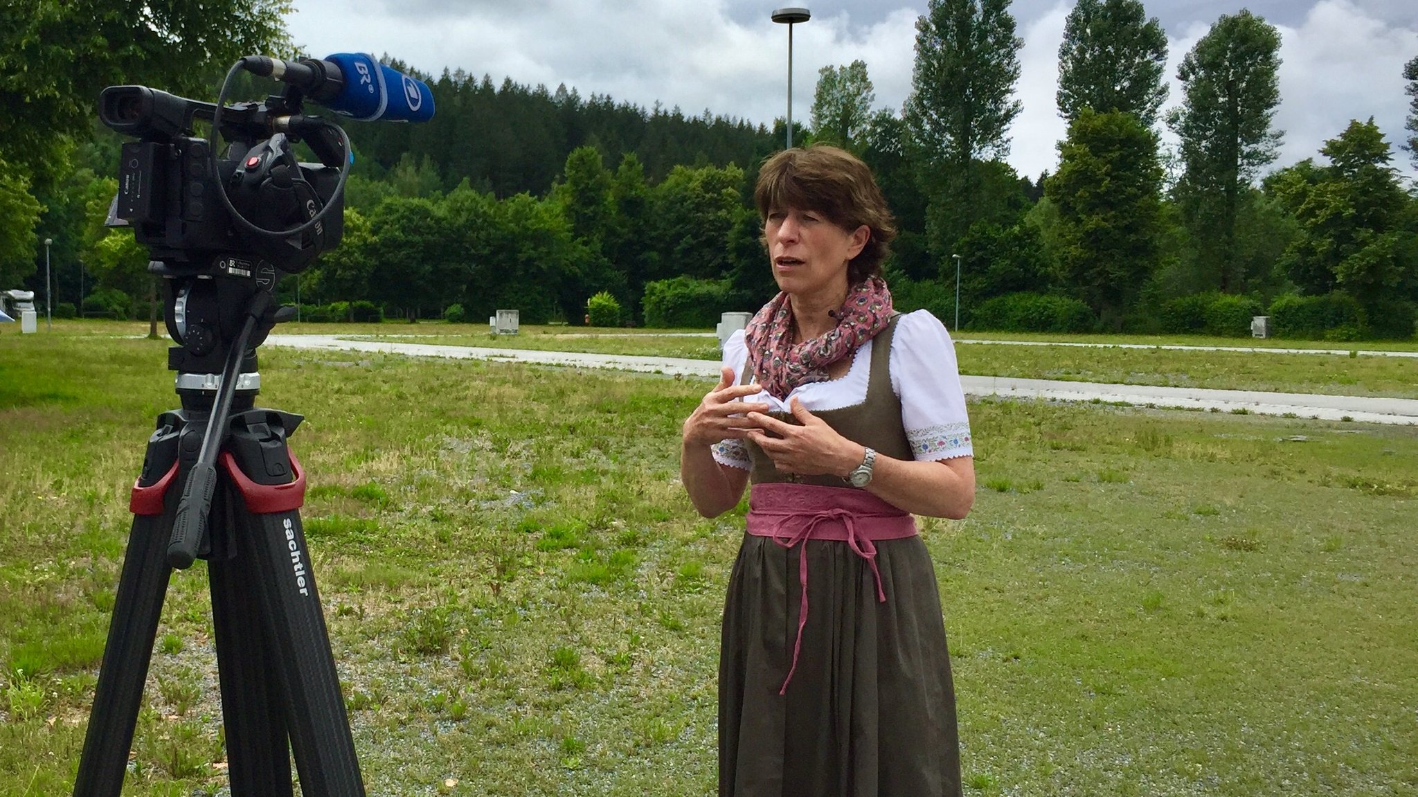 Eine Frau im Dirndl steht für ein Interview vor einer BR-Kamera