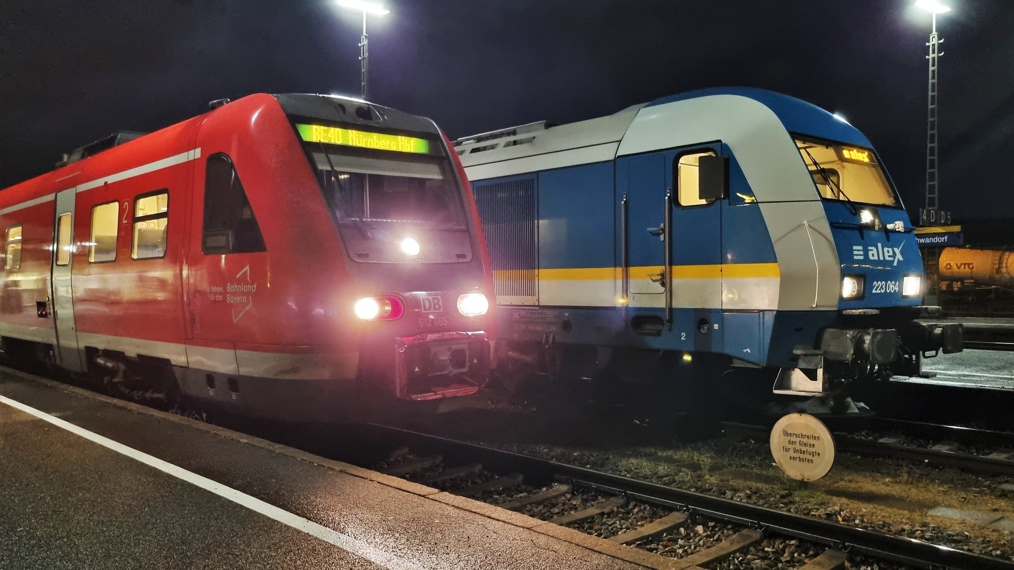 Ein DB-Zug neben einem Alex im Bahnhof.