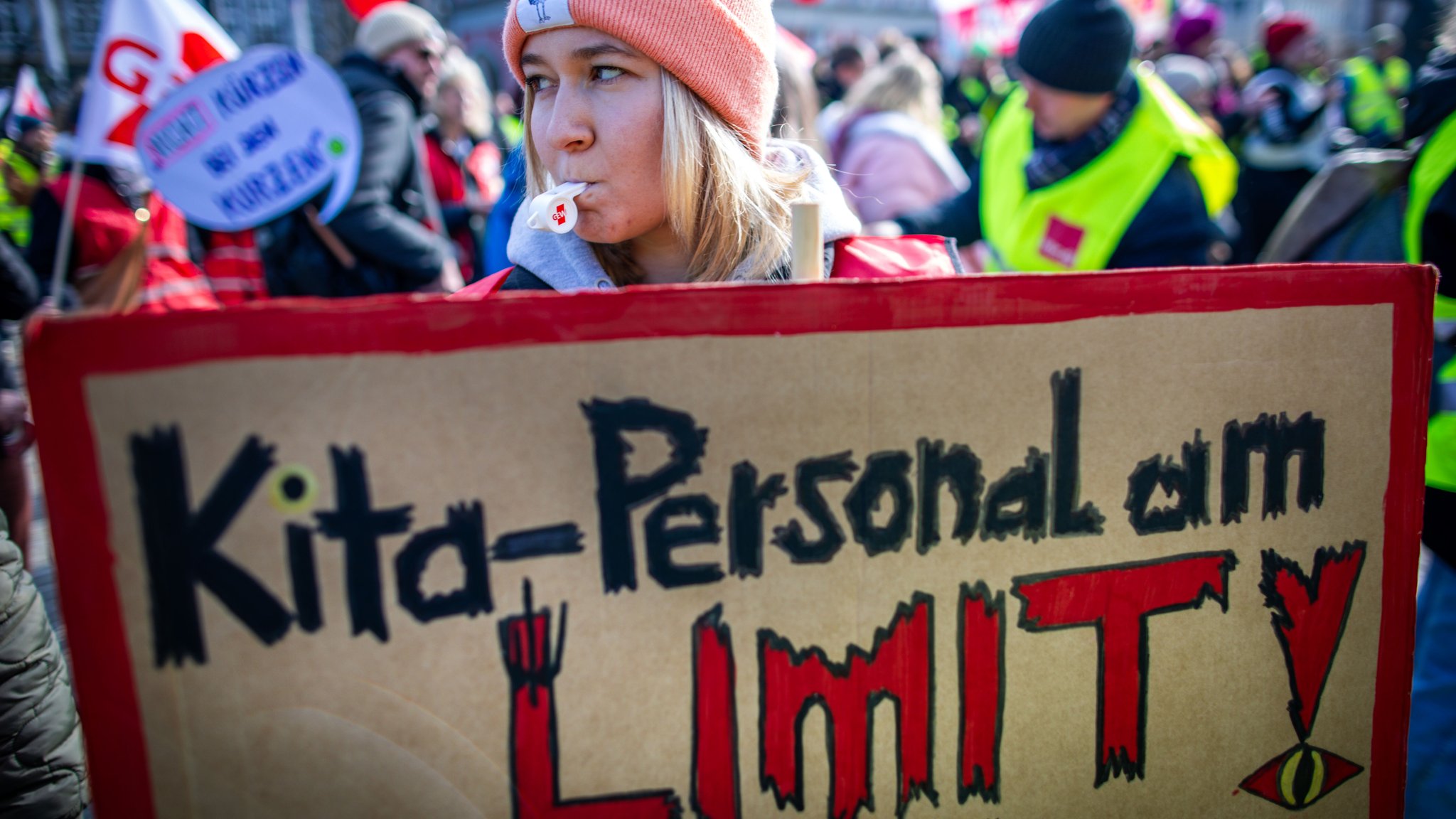 Eine Erzieherin steht mit einem Schild mit dem Schriftzug "Kita-Personal am Limit" bei einer Kundgebung der Gewerkschaft Verdi 