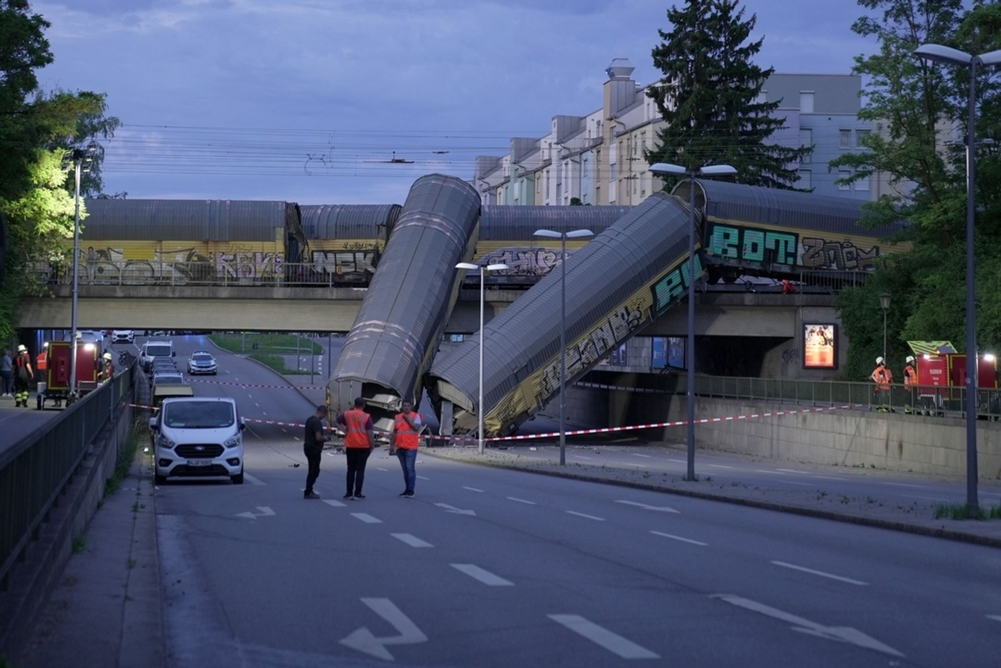 20.06.2026, Bayern, München: Zwei Waggons eines Güterzugs liegen auf einer Straße, nachdem sie von einer Brücke gestürzt sind. | Bild: Ehsan Monajati/dpa 20.06.2026, Bayern, München: Zwei Waggons eines Güterzugs liegen auf einer Straße, nachdem sie von einer Brücke gestürzt sind.