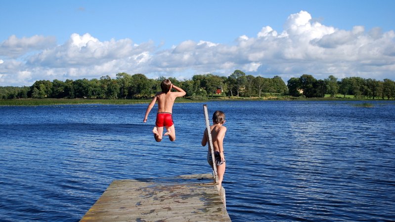 Kinder springen in den Badesee. | Bild: stock.adobe.com/tinadefortunata Kinder springen in den Badesee.