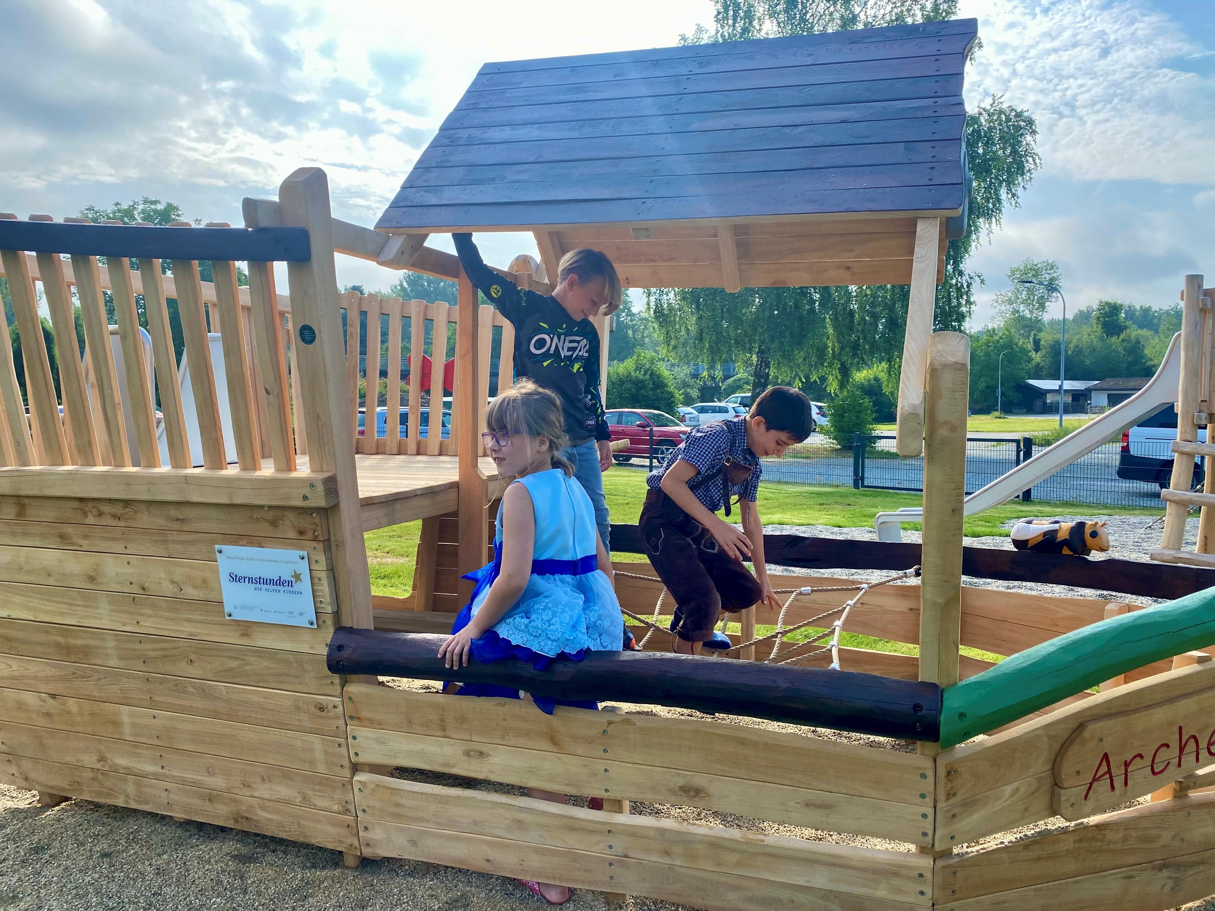 Drei Kinder sitzen in einem Spielgerät und klettern. 