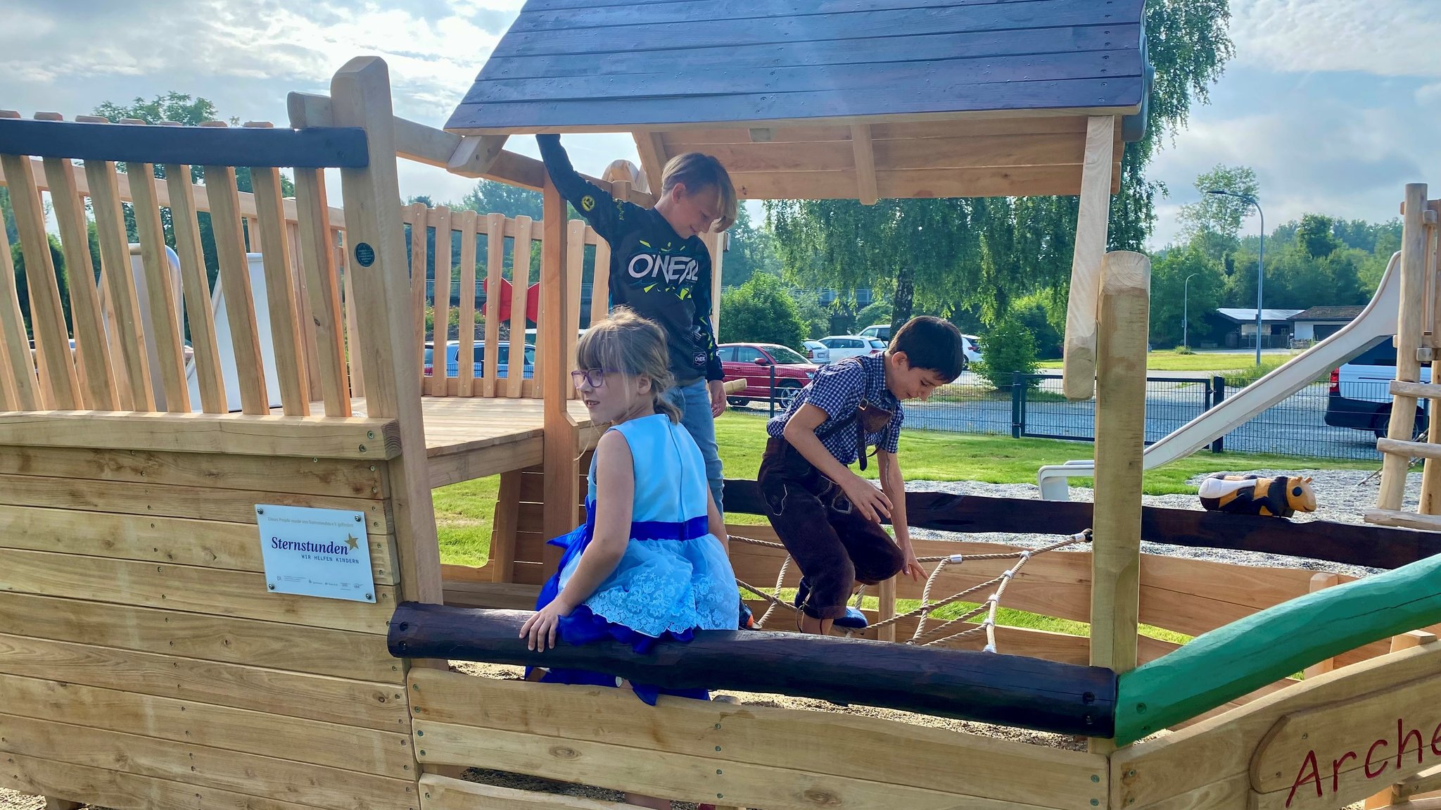 Drei Kinder sitzen in einem Spielgerät und klettern. 