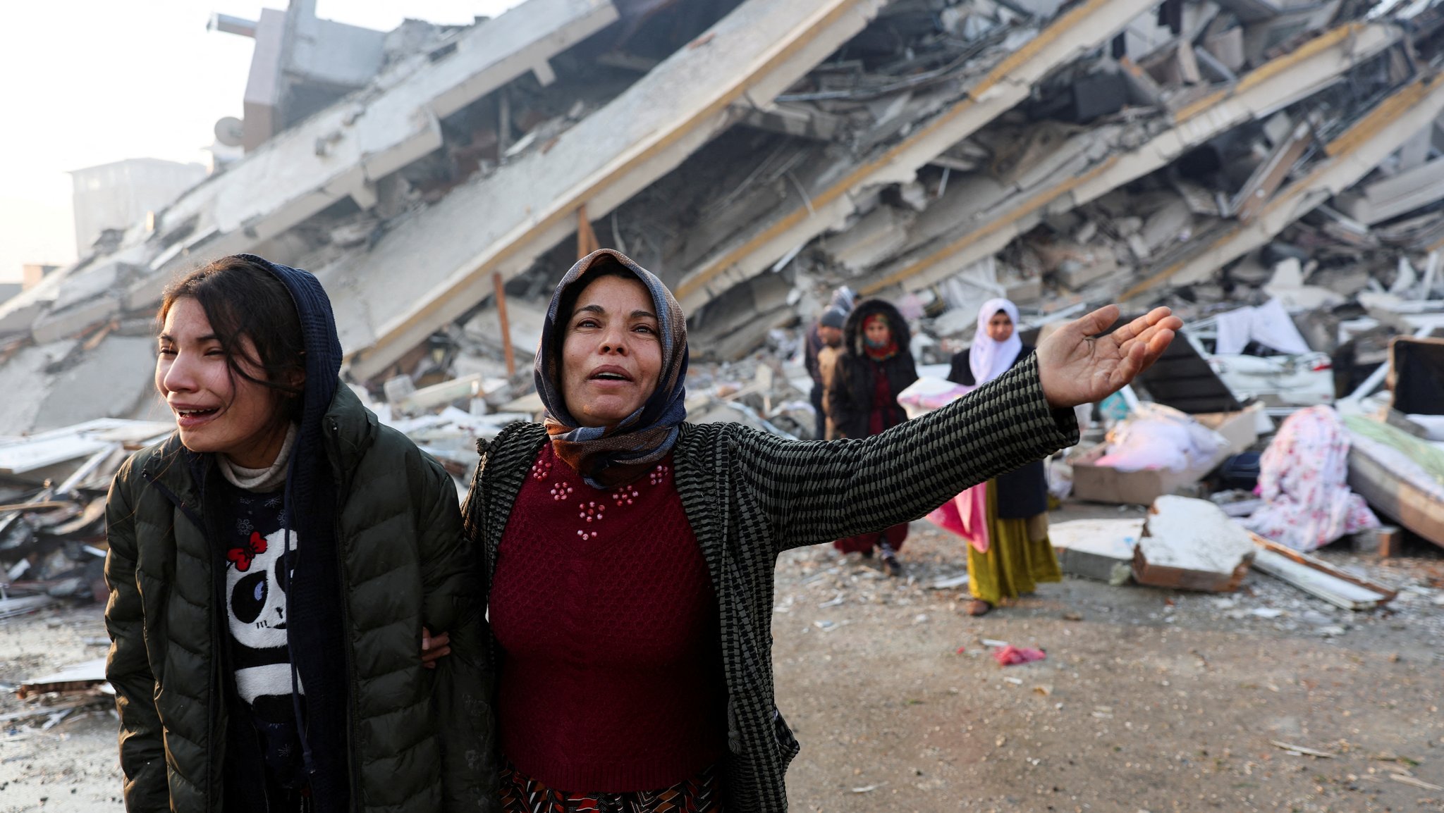 Frauen vor einem zerstörten Haus in Hatay, Türkei